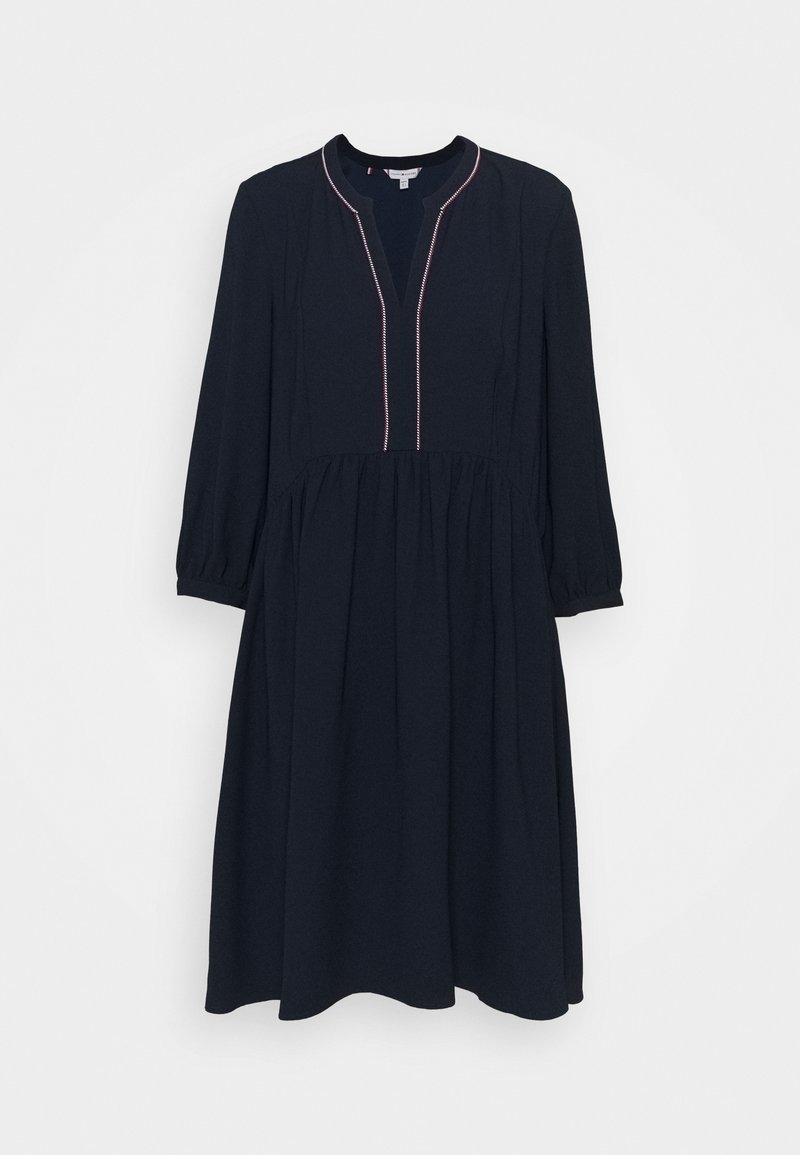 Marineblauwe jurk met een knoopsluiting en roze stiksels, halflange mouwen en een uitlopende rok. Gemaakt van zachte stof met een gladde textuur.