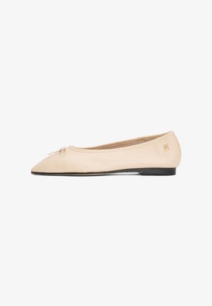 Ballerine en cuir beige, design à bout pointu, fine semelle noire, avec un petit nœud à l'avant et un accent de logo doré.