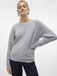 Maglione grigio chiaro lavorato a maglia con collo rotondo, polsini e orlo a costine, abbinato a jeans blu scuro. Tessuto morbido, vestibilità casual.