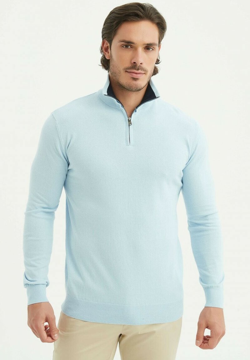 Un pull bleu clair avec un col zippé et des manches longues, fabriqué en tissu tricoté texturé, avec une finition de col sombre contrastant.