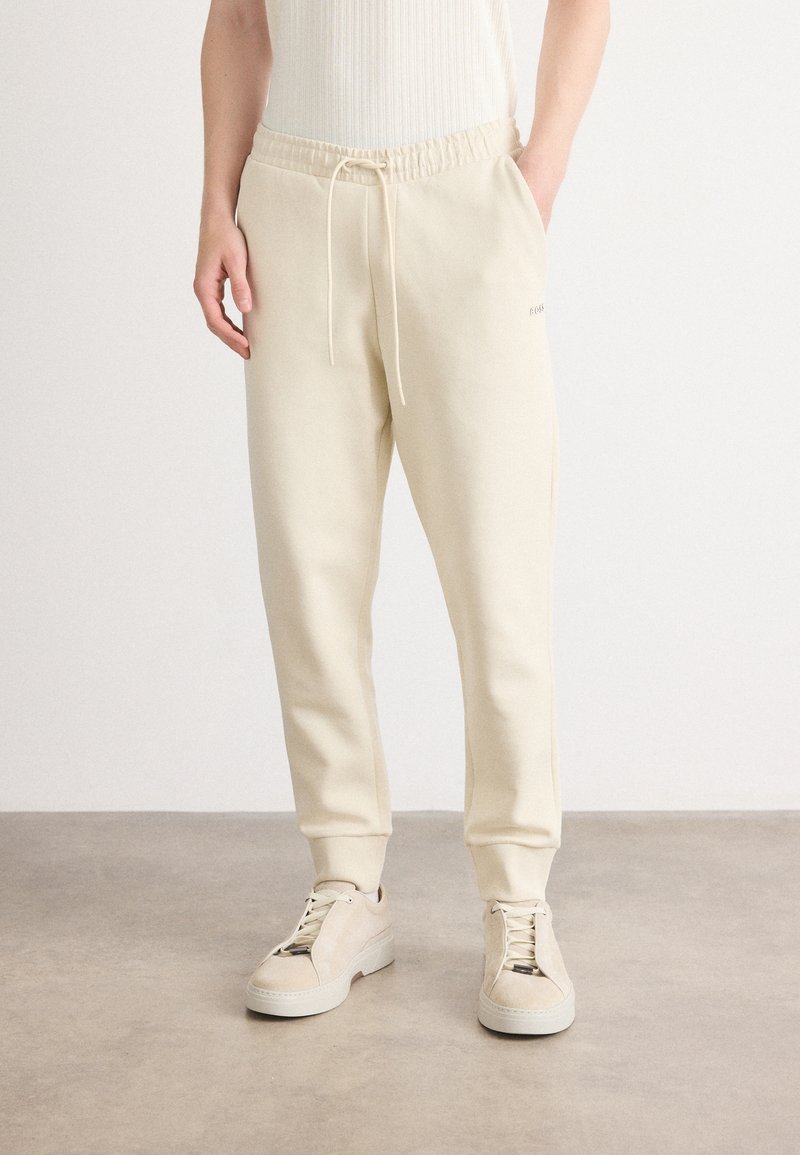 Crèmekleurige sweatpants van zacht materiaal, met een elastische tailleband met koord en zijzakken, tapered leg design.