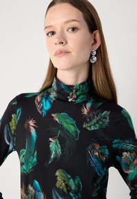 Cămașă cu gât înalt de culoare neagră, cu un imprimeu colorat de pene în nuanțe de verde, albastru și maro, confecționată dintr-un material neted cu un design ajustat.