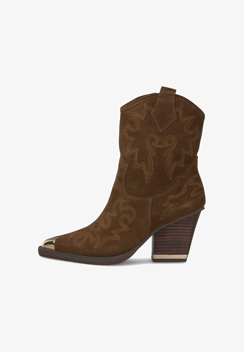 Bottine en daim marron avec bout pointu, motifs de couture décoratifs et embout métallique. Dotée d'un talon en bois empilé.