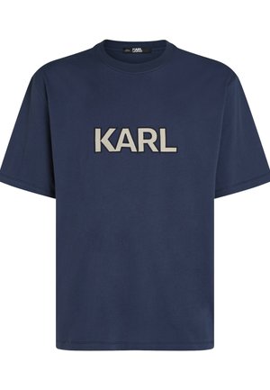 Tummansininen puuvillainen t-paita, jossa on pyöreä kaula-aukko ja lyhyet hihat. Rintakehässä on hyvin näkyvä beige "KARL" -kirjailu.
