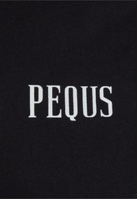 Melns audums ar vārdu "PEQUS" treknrakstā baltās burtnēs. Tekstūra izskatās gluda ar vienkāršu, mūsdienīgu dizainu.