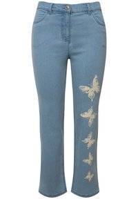 Jeans de mezclilla azul claro con corte recto, que presentan un diseño de patrones de mariposas color crema en la pierna izquierda y un clásico diseño de cinco bolsillos.