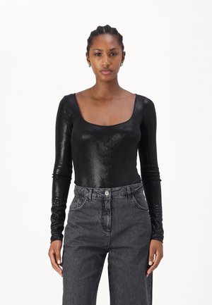 Body nero a maniche lunghe realizzato in un materiale lucido con scollatura quadrata, abbinato a jeans scuri grigi a vita alta.