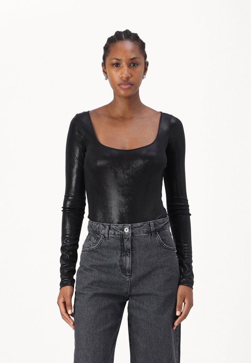 Body nero a maniche lunghe realizzato in un materiale lucido con scollatura quadrata, abbinato a jeans scuri grigi a vita alta.
