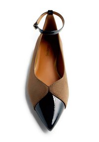 Ballerines en suède marron avec un bout pointu en vernis noir et une bride de cheville noire, mettant en valeur un design épuré et des textures contrastées.