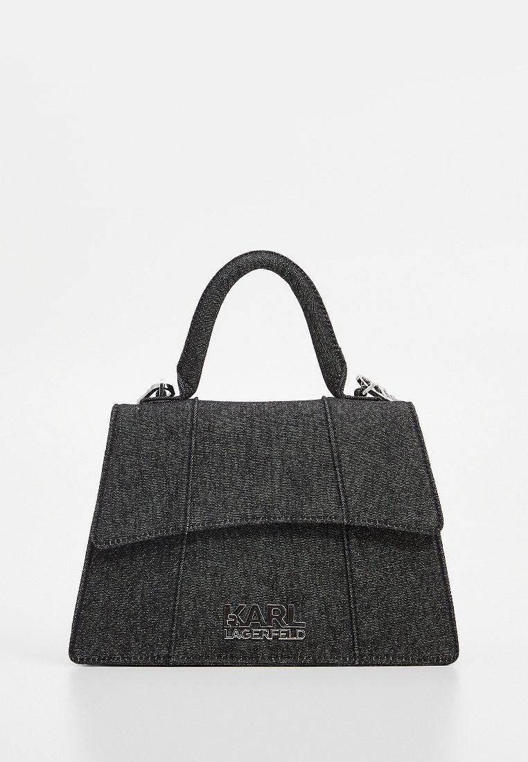 Sac à main en denim noir avec un design structuré, fermeture à rabat et accent logo argenté. Il dispose d'une courroie courte et incurvée ainsi que d'une surface texturée.