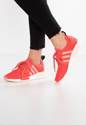 Red textile athletic shoes with three white stripes, lace-up design, and black heel tab; rubber outsole, featuring a cushioned midsole.