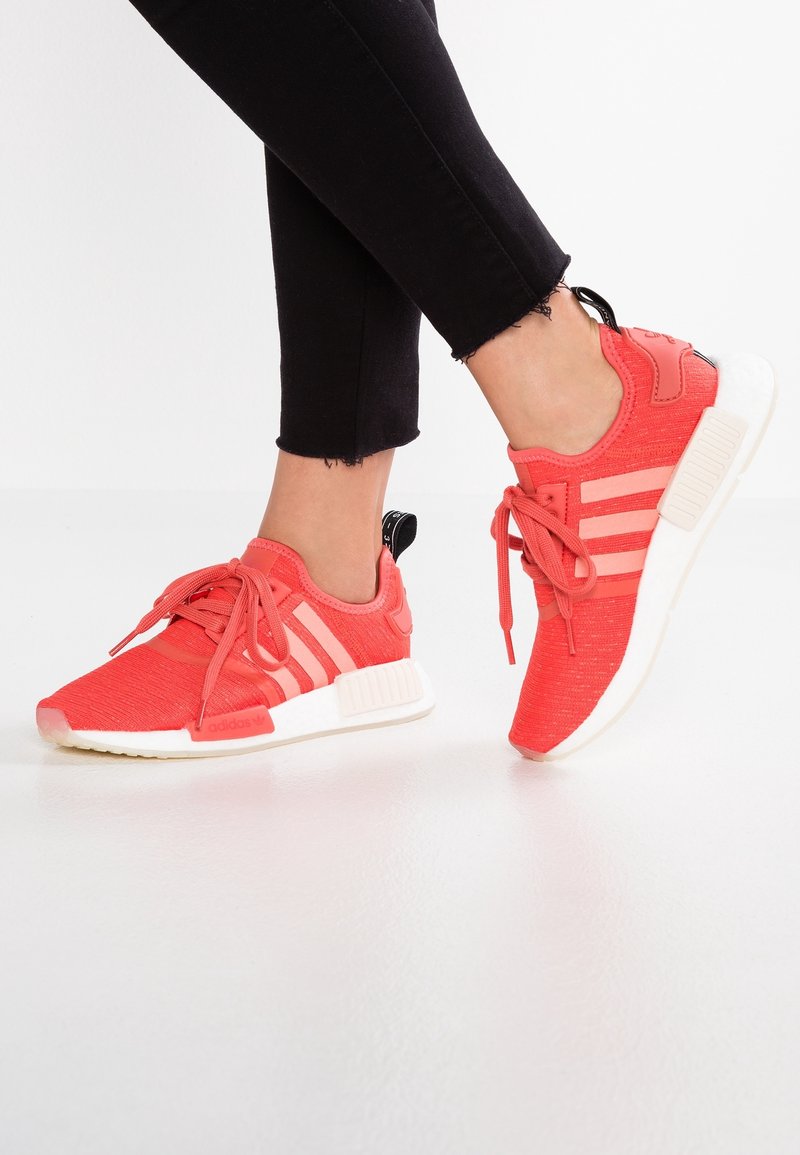 Červené textilní sportovní boty s třemi bílými pruhy, šněrovací design a černý opatek; gumová podrážka s polstrovanou mezipodrážkou.