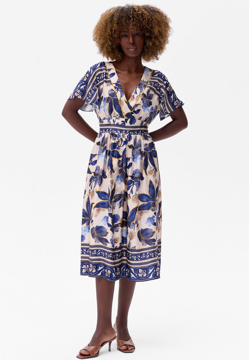 Bloemen midi-jurk met een diepe V-hals, korte mouwen en een getailleerde taille. Beschikt over blauwe en crèmekleurige tinten, gedetailleerde randpatronen en een gladde stof.