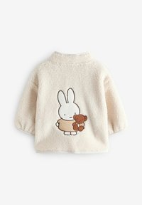 Veste polaire couleur crème à manches longues avec un lapin blanc brodé tenant un ours en peluche marron dans le dos.