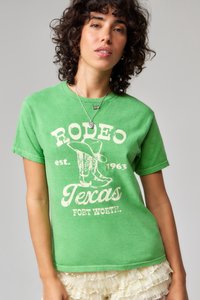 Zöld pamuttartalmú póló, amely vintage rodeó grafikát ábrázol cowboy csizmákkal és "Rodeo Texas est. 1963" felirattal elhasználódott fehér nyomtatással.