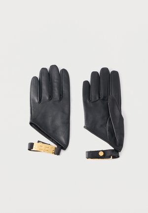 Para czarnych skórzanych rękawiczek z paskami na złote klamry, pokazanych na płasko, z dłońmi skierowanymi do dołu na jasnym, jednolitym tle.