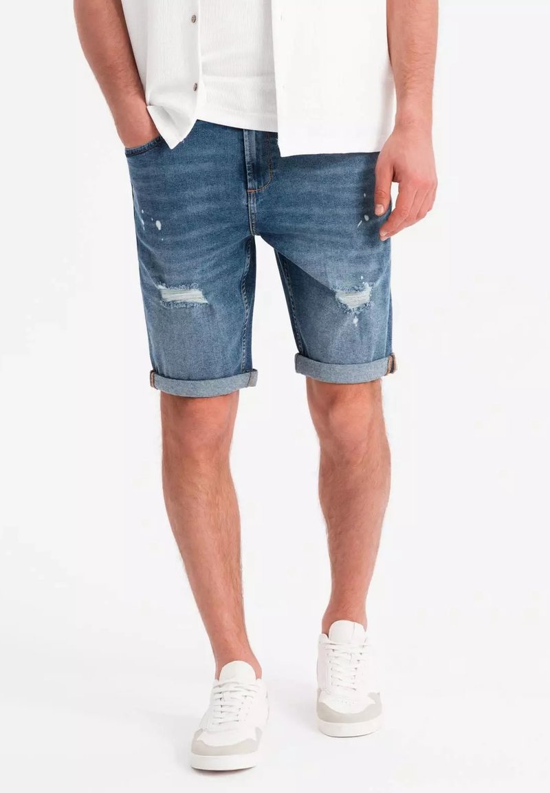 Jeansshorts i ljusblått med urtvättade och slitna partier, uppvikta fållar och fem fickor, i kombination med vita sneakers.