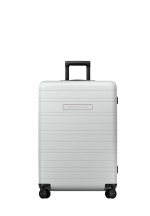 Hard-shell silver suitcase with horizontal grooves, black wheels, and a retractable handle. Smooth texture, minimalistic design.