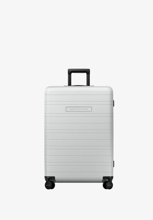 Hard-shell silver suitcase with horizontal grooves, black wheels, and a retractable handle. Smooth texture, minimalistic design.