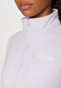 Svetlo lilavi flis pulover z visokim ovratnikom in polovičnim zadrgo, z teksturirano tkanino in izvezenim logotipom "TERREX" v usklajeni barvi.