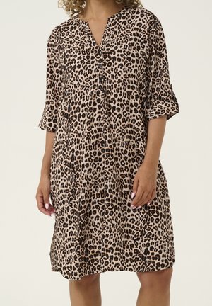 Kvinde iført en knælængde leopardprint kjole med op-rullede 3/4 ærmer og knapper foran.