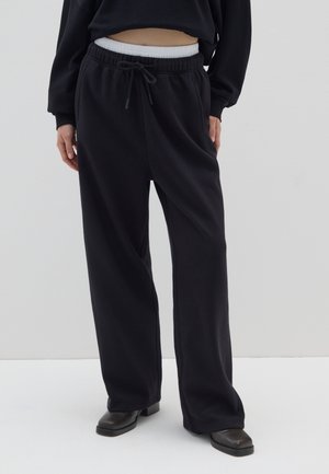 Pantaloni della tuta neri a gamba larga con una vita elastica bianca e stringi vita. Materiale morbido, con tasche laterali e vestibilità comoda.