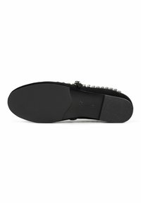Suela de zapato de ante negro con textura suave y forma redondeada. Presenta una fila de acentos metálicos a lo largo del borde superior para aportar detalle.
