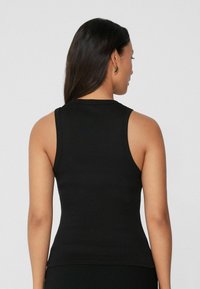 Débardeur noir côtelé au design ajusté. Doté de bretelles fines et d'un tissu texturé subtil pour le confort et la respirabilité.