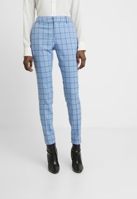 Light blue plaid trousers with a tailored fit, featuring a smooth texture and a high waistband. Paired with black ankle boots.