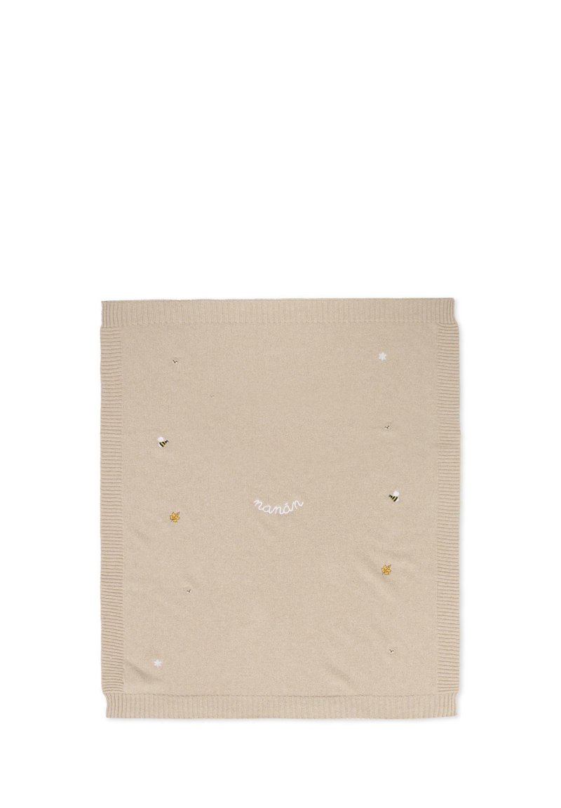 Coperta in maglia beige con bordi a coste, decorata con api ricamate, una foglia e stelle, con la parola "nanán" in un carattere bianco curvo.