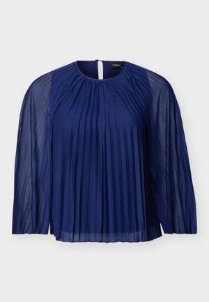 Μπλε ναυτικό πουκάμισο με πτυχώσεις, διάφανα μακριά μανίκια και στρογγυλή λαιμόκοψη, με κλείσιμο πίσω με κουμπί σε σχήμα κλειδαρότρυπας.