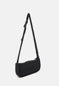 Černá ramenní taška obdélníkového tvaru, vyrobená z texturované tkaniny. Má dlouhý nastavitelný popruh a zipové uzavírání na vrchu.