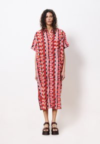 Kurzärmliges, knöpfbares Kleid mit einem lebendigen geometrischen Muster in Rot und Pink. Hergestellt aus leichtem Stoff, mit einem lässigen Schnitt und knielanger Länge.
