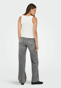 Hvid ærmeløs tanktop parret med høj-tailet, løs passende grå jeans, der har to baglommer og en lige ben-design.