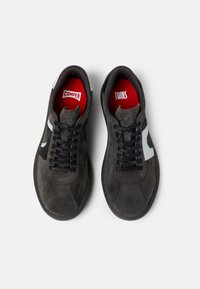 Svarta mockasneakers med mörka snören, vita detaljer och röda innersulor med logotyperna "Camper" och "Twins". Rundad tådesign.