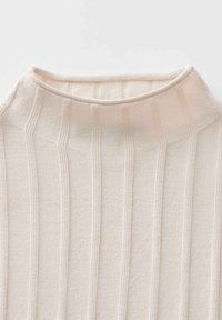 Pull en maille côtelée beige avec une texture douce, présentant des rayures verticales et une coupe ajustée autour du col.