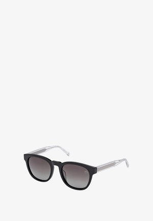 Occhiali da sole con montatura nera a forma quadrata, lenti scure con gradiente e bracci trasparenti con texture rigata, su uno sfondo bianco.