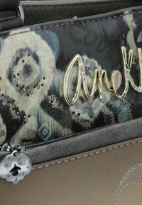 Handtasche mit einem metallisch goldenen "Amélie"-Akzent, tierischen Drucktexturen in Schwarz und Türkis sowie einer grauen strukturierten Lederbasis mit silbernen Beschlägen.