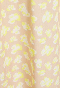 Blommönstrad tyg med persikobakgrund, som har mönster av vita och klara gula blommor, texturerad yta, lätt material.