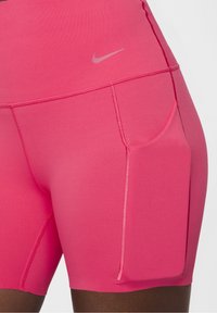 Różowe spodenki sportowe z gładkiego, elastycznego materiału. Posiadają boczną kieszeń oraz subtelne logo Nike w jaśniejszym odcieniu różu.