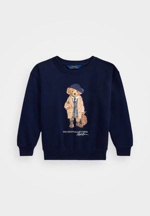 Felpa blu marino con polsini e orlo a costine, caratterizzata da una grafica di un orso in abbigliamento, che tiene una borsa. Testo "Polo Bear by Ralph Lauren" incluso.