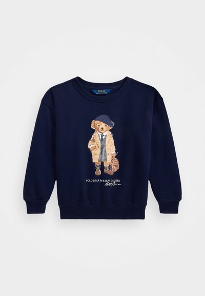 Mörkblå sweathoodie med ribbade muddar och nederkant, med en grafik av en björn i kläder som håller en väska. Texten "Polo Bear by Ralph Lauren" ingår.