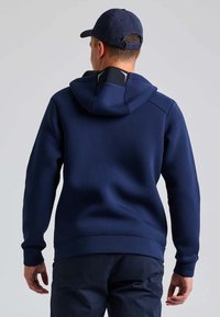 Felpa blu navy realizzata in tessuto texturizzato, con cappuccio regolabile e fodera interna a contrasto, caratterizzata da una vestibilità slim e polsini a costine.