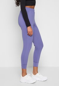 Slim-fit dresowe spodnie w jasnym lawendowym kolorze, wykonane z elastycznego materiału. Posiadają elastyczny pas, prążkowane mankiety i subtelne detale szwów.