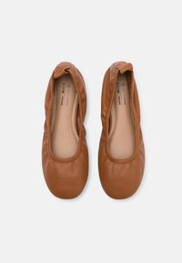 Braune vegane Lederballet flats mit weichem, abgerundetem Zehenbereich und elastischem Einstieg. Glatte Textur mit dezenten Steppnähten.