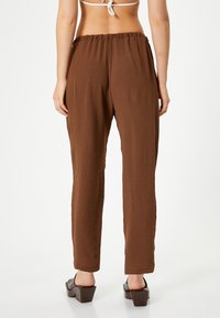 Bruine, lichte, casual broek met een gestructureerde afwerking, elastische tailleband en rechte pijpen. Geldig in combinatie met chunky sandalen met hak.