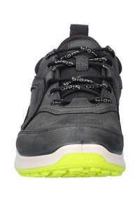 Sneaker grigio scuro con lacci neri, suola centrale bianca e suola testurizzata gialla brillante, visto frontalmente.