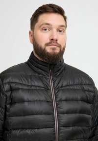 Juodas pūkuotas džemperis su horizontaliais siūlėmis ir aukštu apykakle, su centriniais užtrauktukais su kontrastingomis detalėmis. Glotnus, blizgus paviršius.