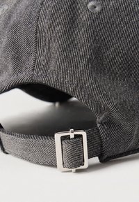 Tuva pelēka auduma beisbola cepures siksniņa ar sudraba taisnstūrveida sprādzi izmēra regulēšanai.