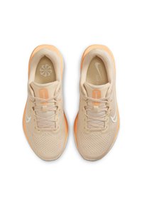Zapatillas deportivas de color beige claro con parte superior de malla, detalles en naranja y una suela texturizada. Presentan una marca prominente y un logo circular en la plantilla.